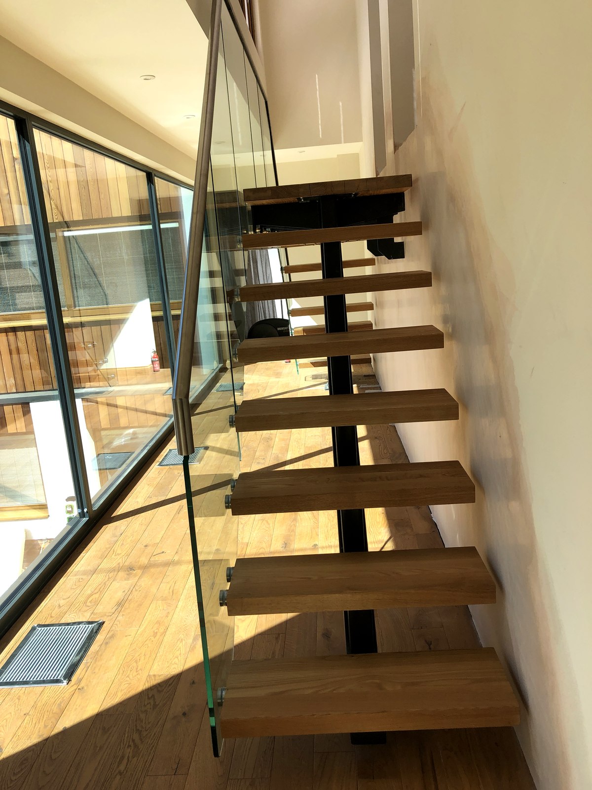 Floating steel-spine staircase with oak treads and frameless glass balustrade, Weybridge, Surrey