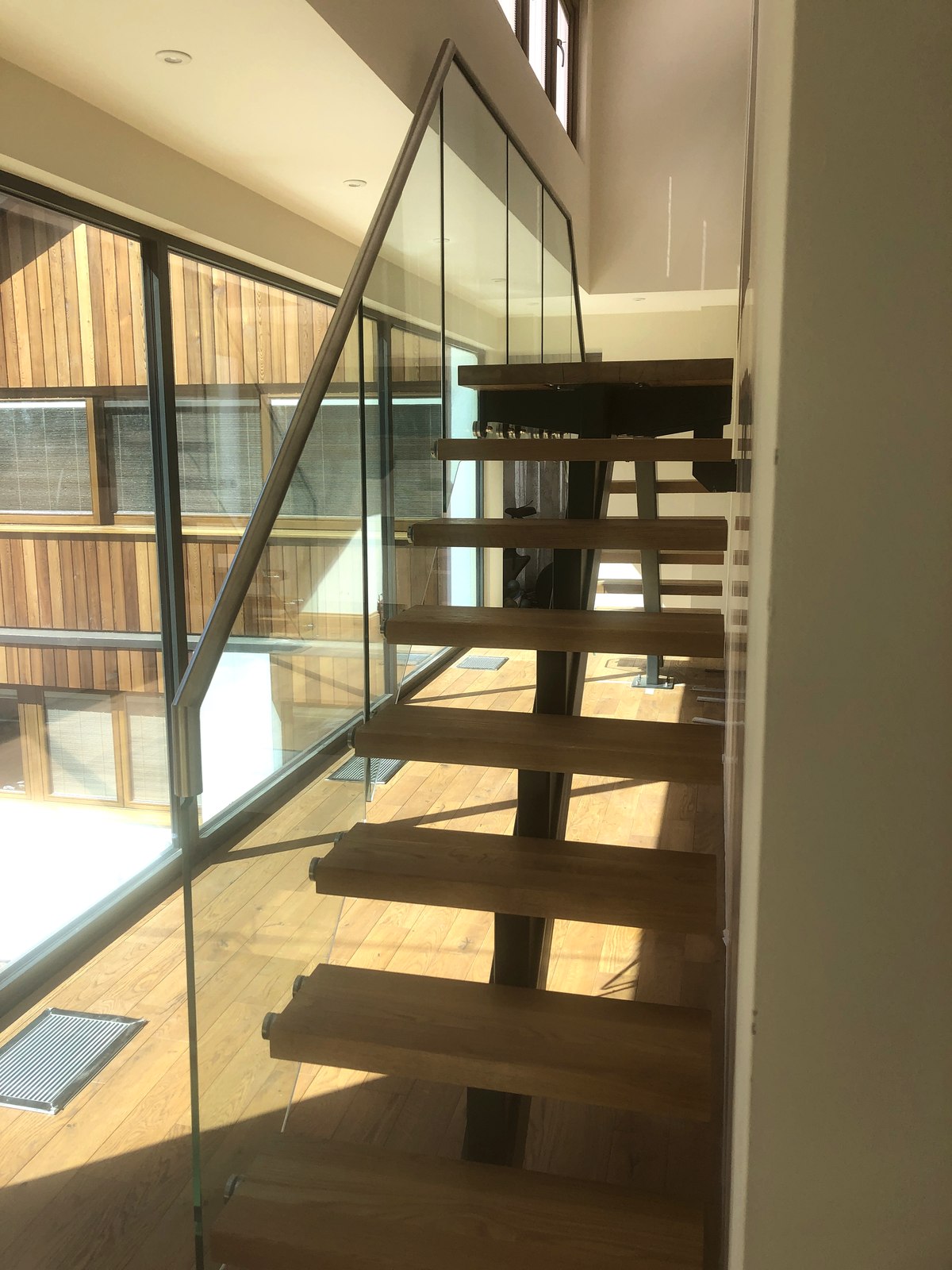 Steel-spine oak and glass staircase rising to a gallery landing, Weybridge, Surrey