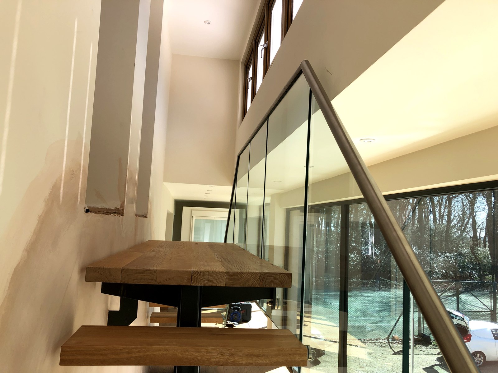 Up-and-over steel-spine staircase with oak treads, glass balustrade and landing, Surrey