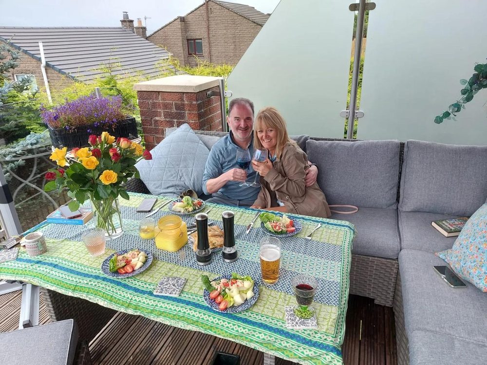 Customers relaxing on a glass and stainless steel walkout balcony supplied by Dio-Met and fitted by the customer, photographed almost fourteen years after installation