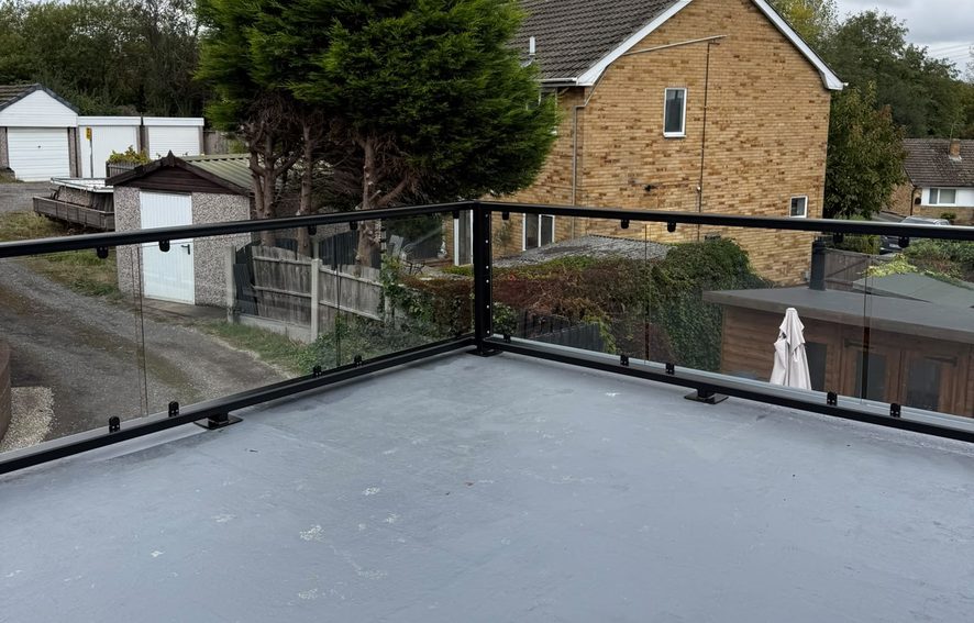 Powder coated steel framed glass balustrade guarding three sides of a flat roof terrace, Barnsley