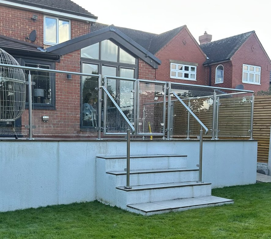Pair of stainless steel and glass gates closed across the head of the steps on a raised patio in Rotherham