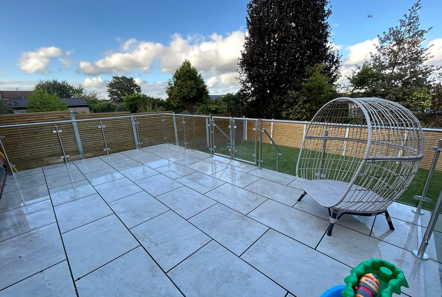 System 1 stainless steel and glass balustrade running round the perimeter of a raised porcelain patio