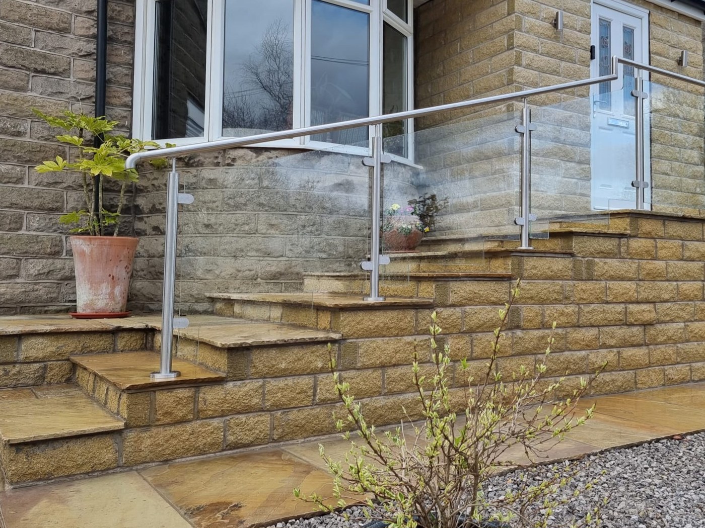System 1 glass balustrade with raking stainless steel handrail following stone garden steps