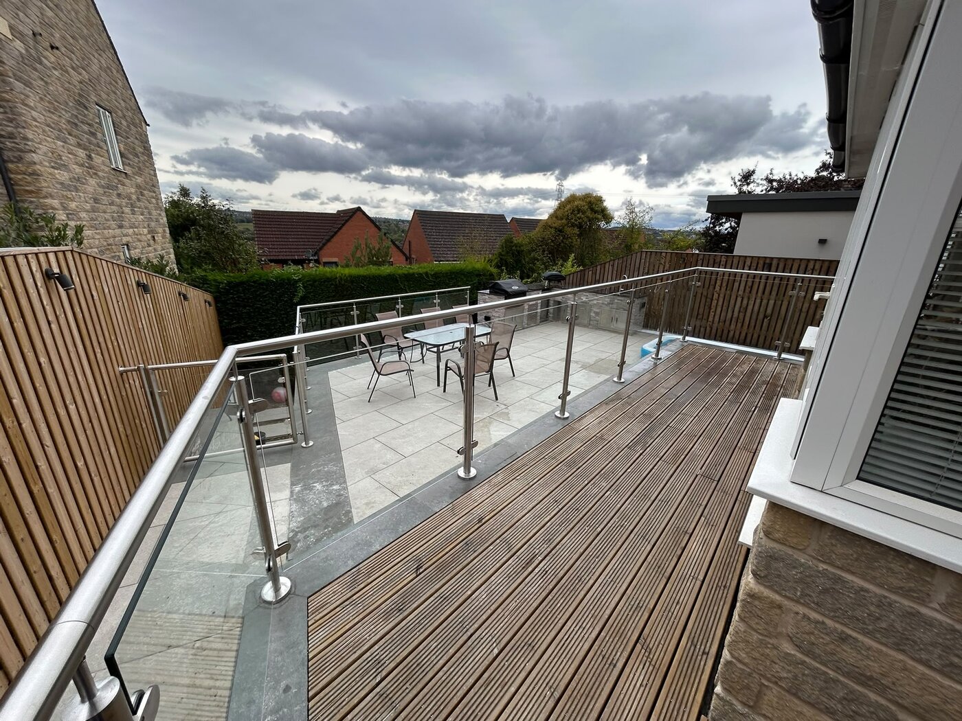 Glass balustrade following the splayed corner of a raised patio with countryside views, South Yorkshire