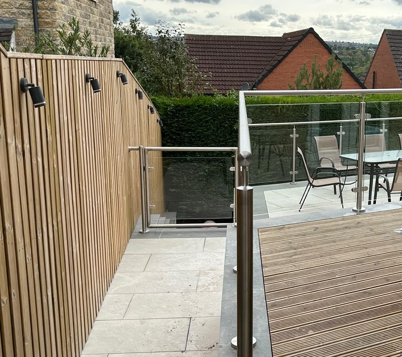 Glass gate in a stainless steel balustrade at the head of steps down from a raised patio, Rotherham
