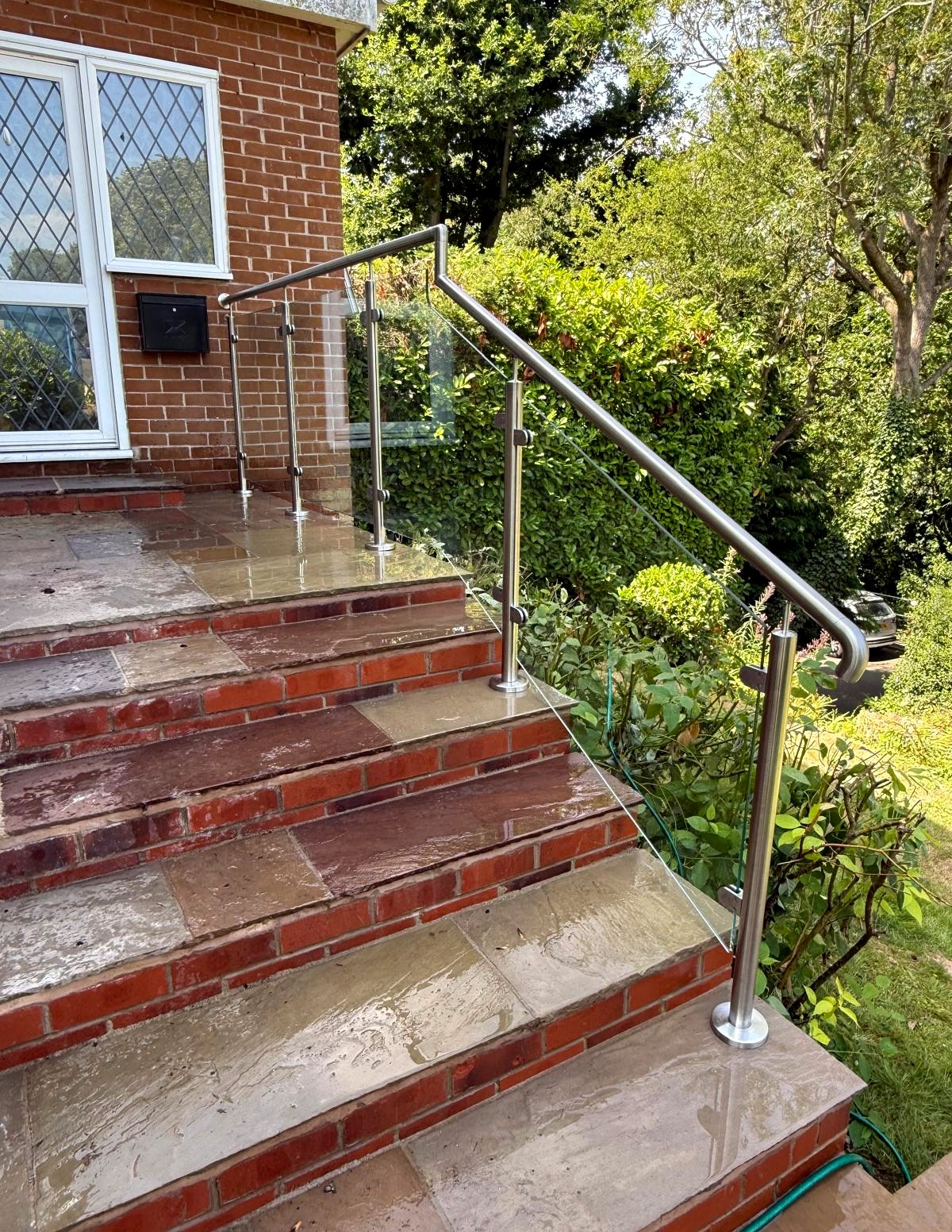 Stainless steel and glass balustrade with a raking handrail to sandstone and brick entrance steps in Walkley, Sheffield