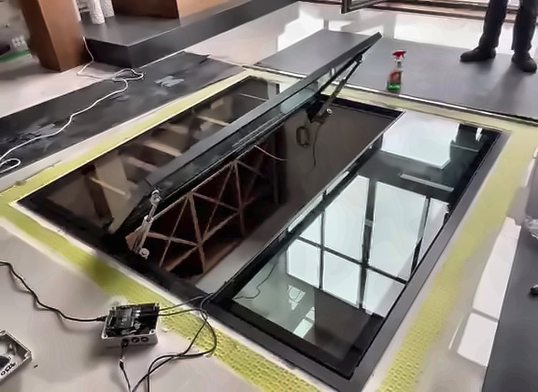 Electric hinged glass floor door open above a wine cellar, Swindon