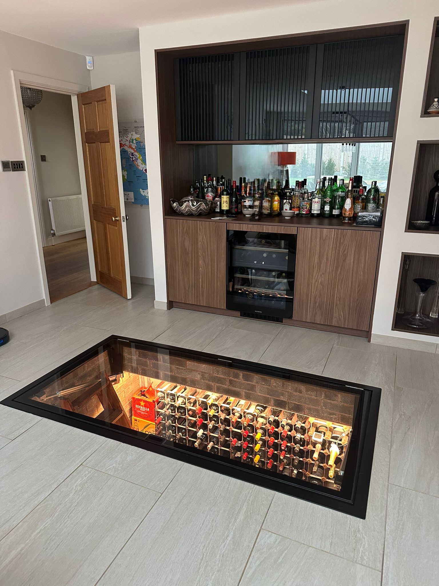 Electric motorised hinged glass floor opening on a linear actuator to reveal a wine cellar below