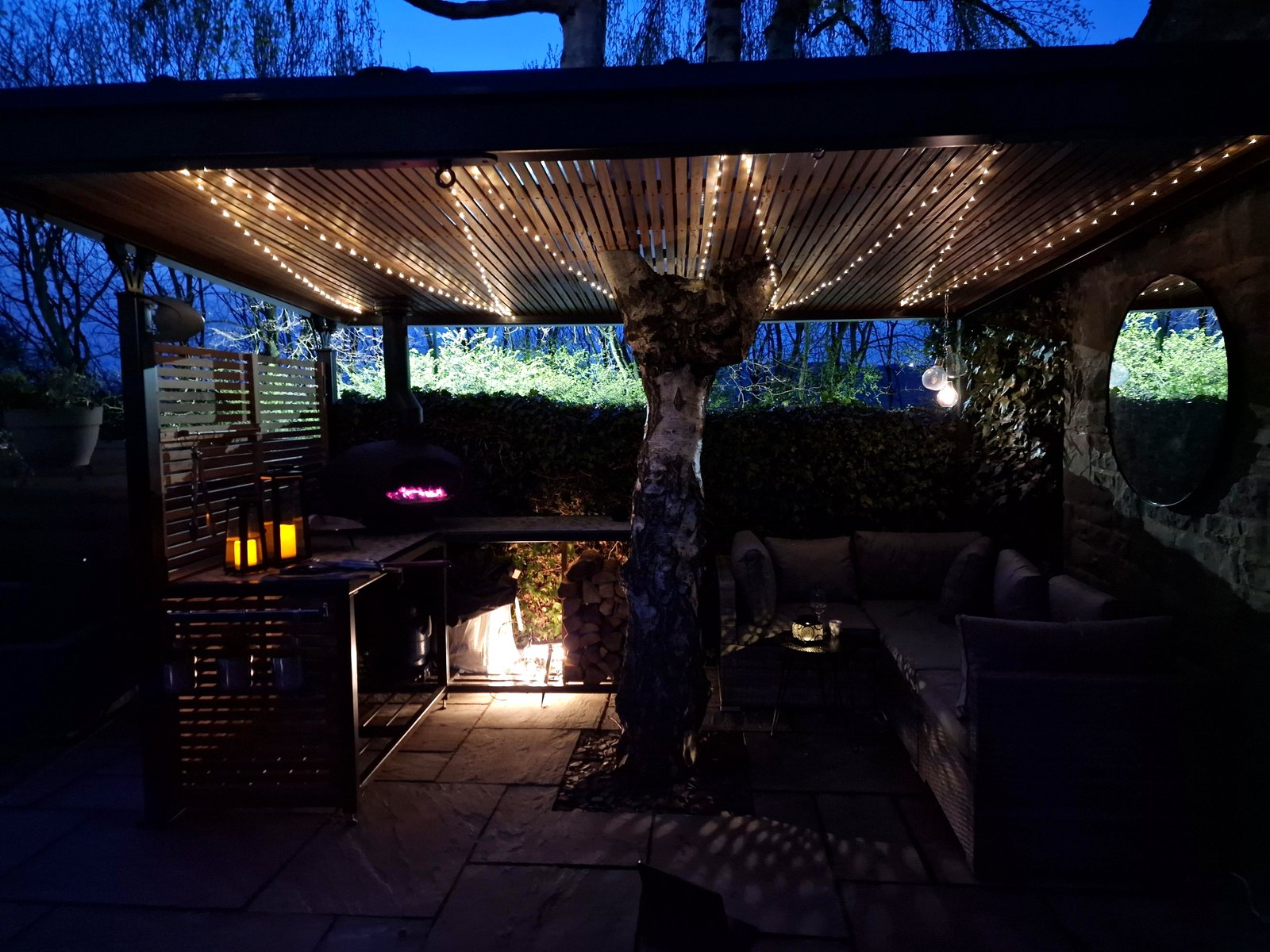 Bespoke steel pergola at night with the pizza oven lit and feature lighting, Sheffield