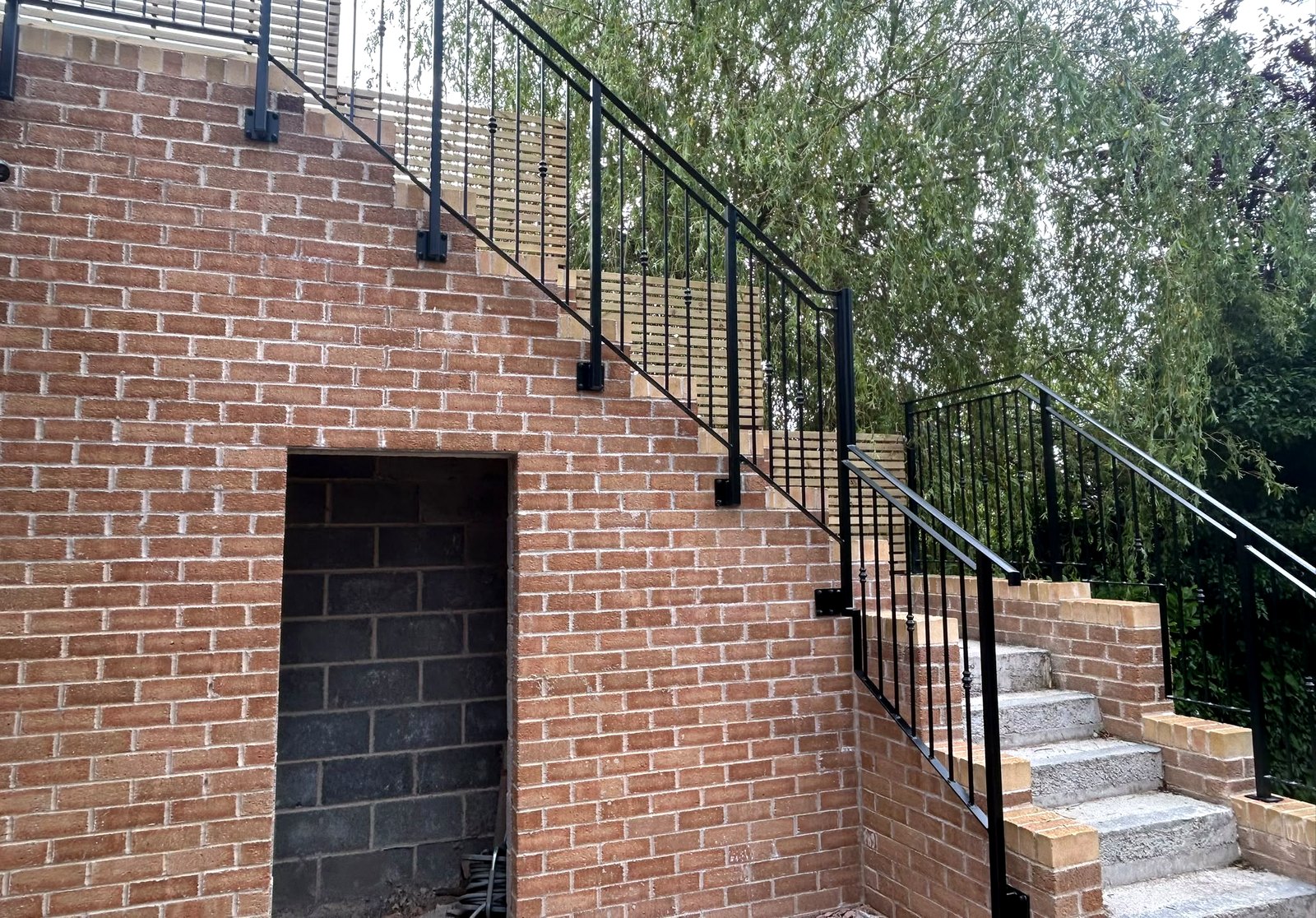 Black metal railings following external garden steps to a lower entrance doorway, Sheffield