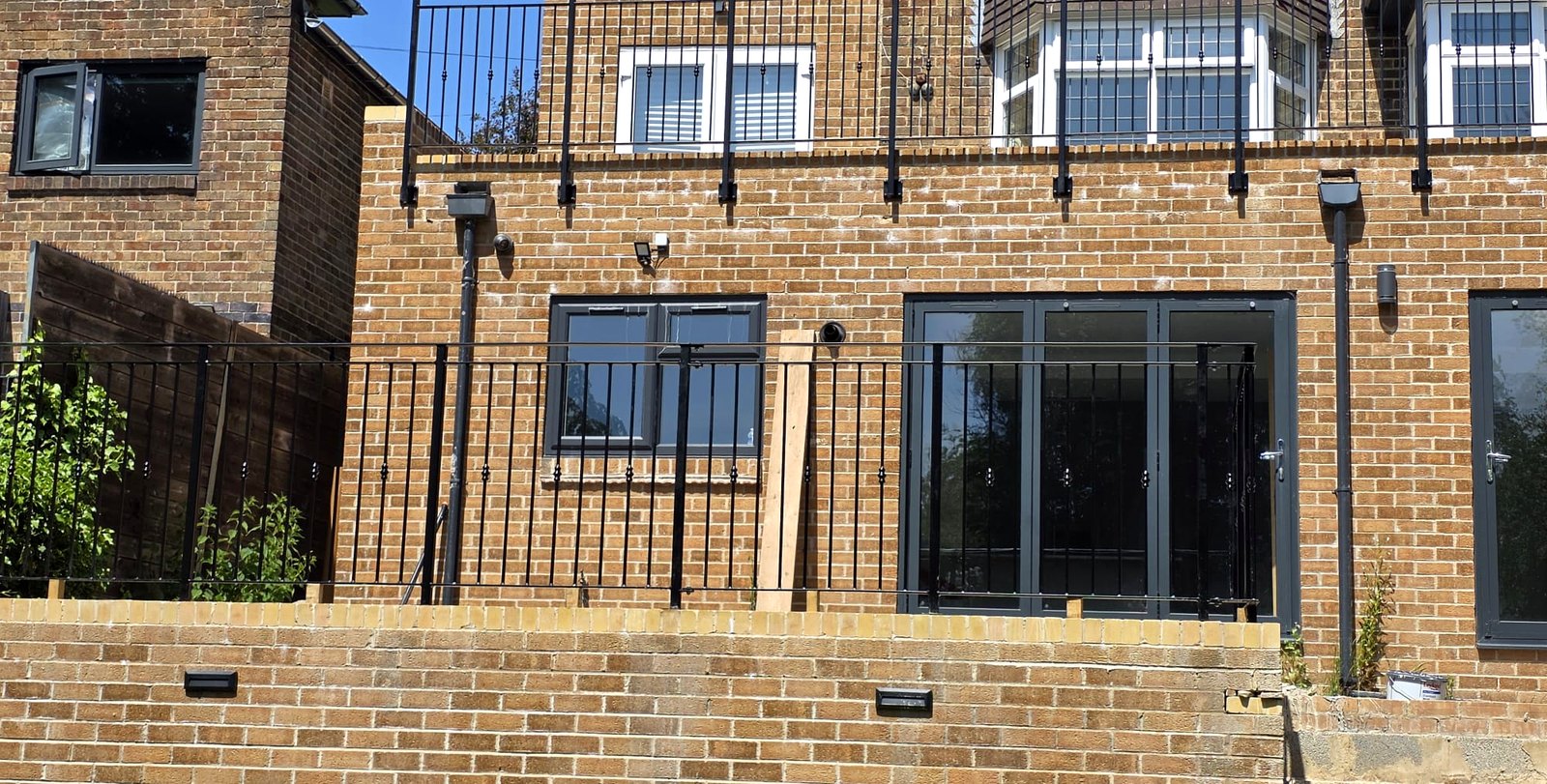 Black metal balustrade railings along a retaining wall above the lower-ground windows, Sheffield