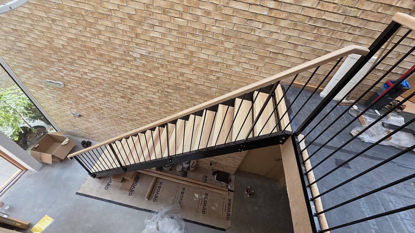 Bespoke steel staircase seen from above showing pressed steel tread trays and ash treads, Manchester