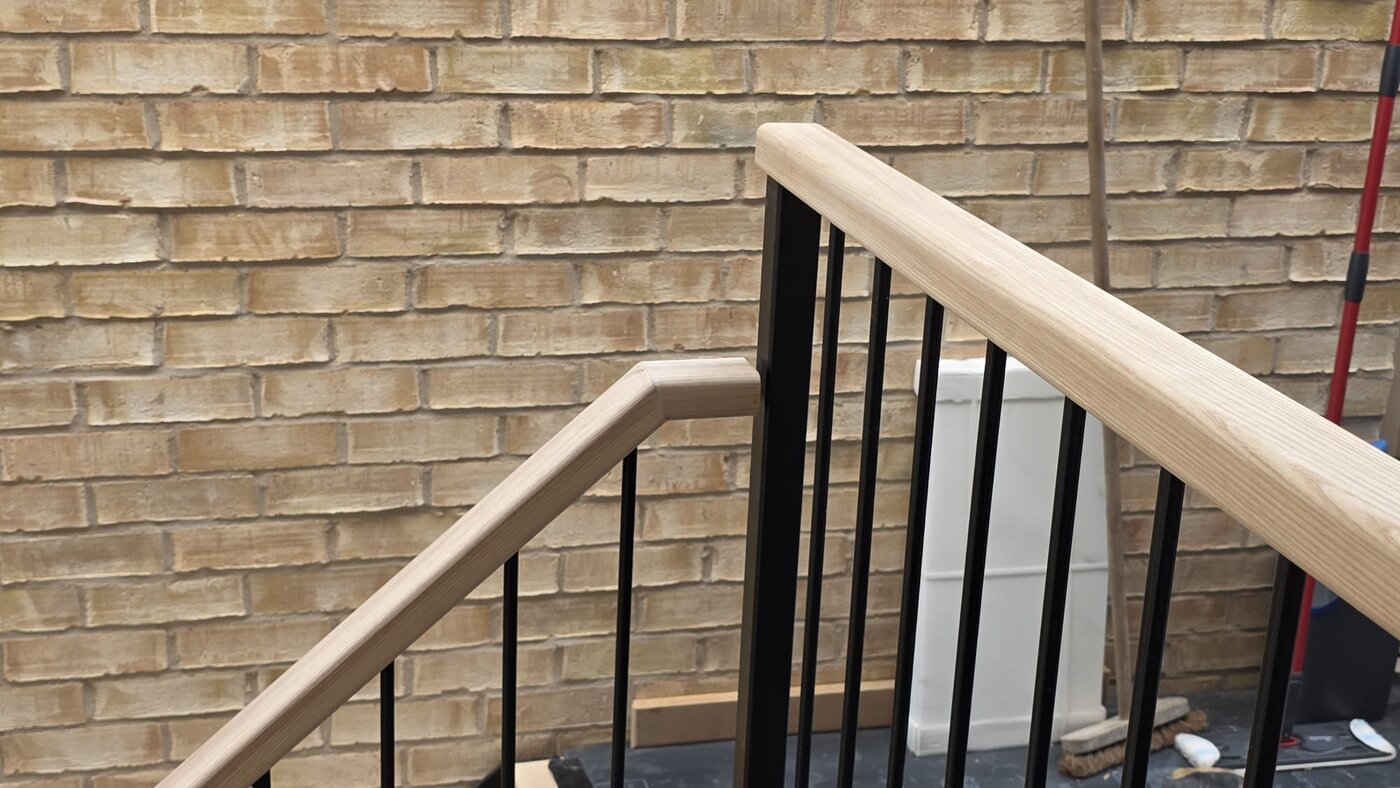 Solid ash handrail mitred over a black powder coated metal balustrade, Chorlton Manchester