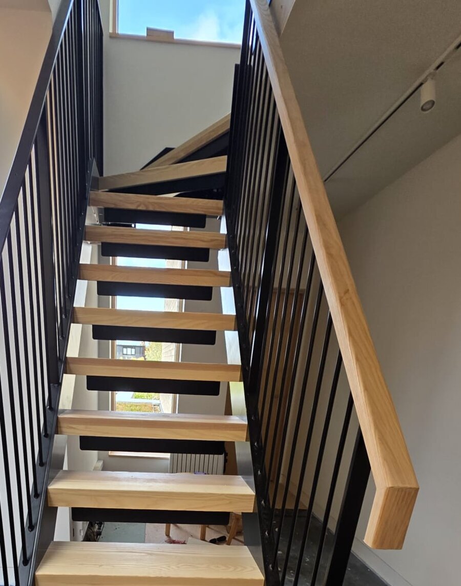 Kite winder turning at the top of a steel staircase with ash treads and black balustrade, Manchester