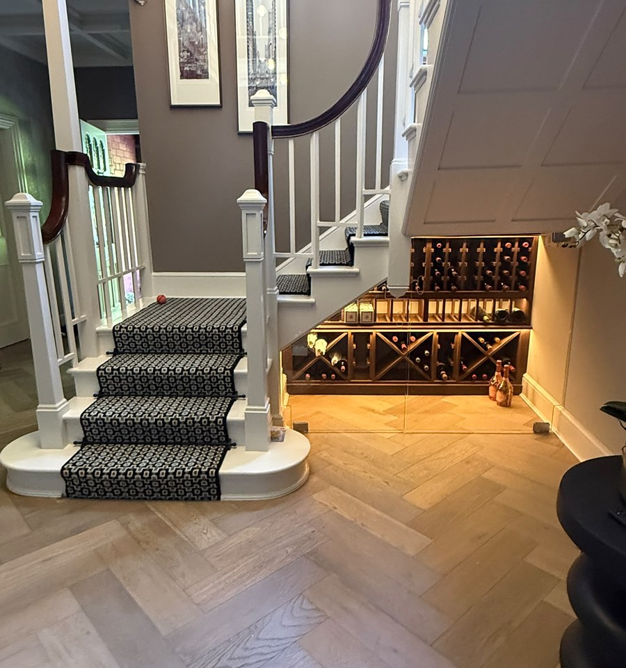 Under stairs glass wine store seen across a herringbone oak hallway floor in Warrington