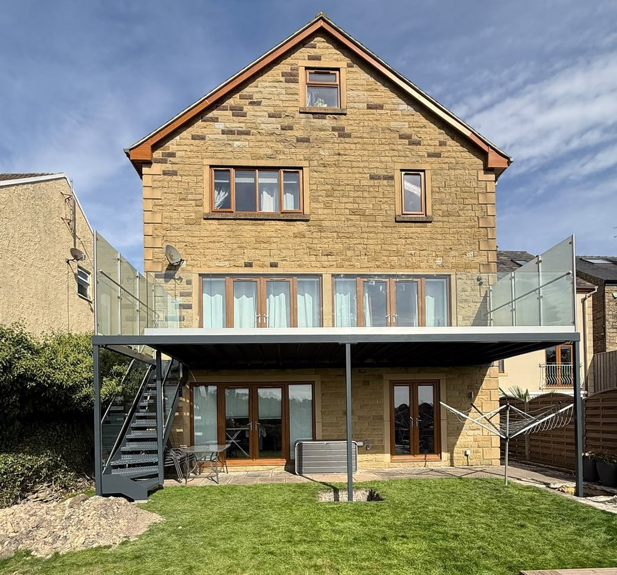 Walk-out balcony and external steel staircase across the rear elevation of a stone house in Dronfield