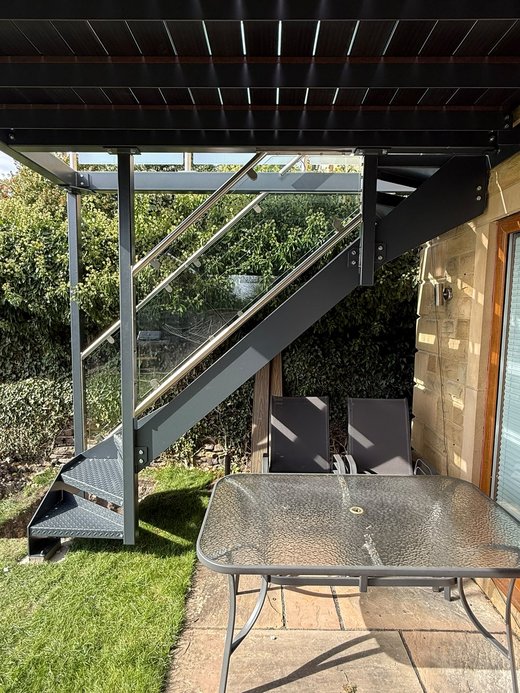 Sheltered paved seating area underneath the walk-out balcony, outside the lower patio doors