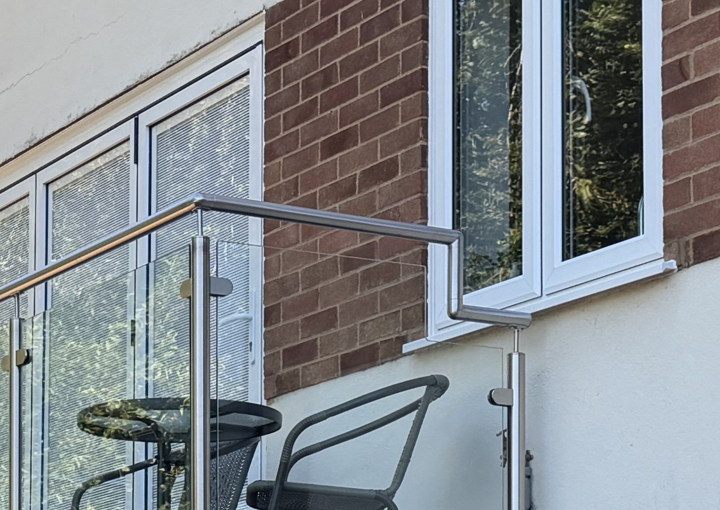 Stainless steel handrail stepped down and returned to the wall to clear an outward opening window above a balcony