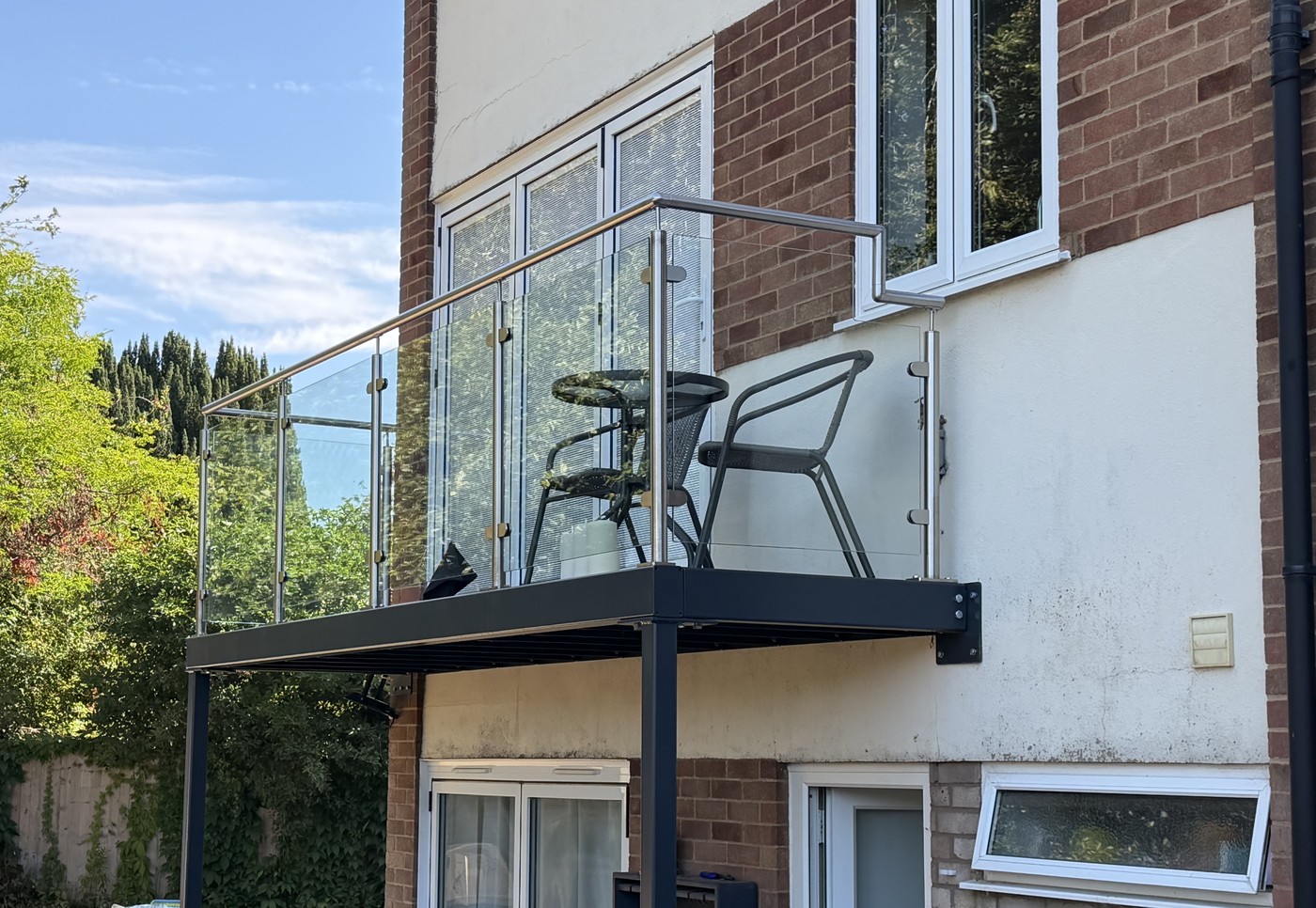 Steel post and welded bracket carrying a stacked walk-out balcony frame on a house in Buckinghamshire