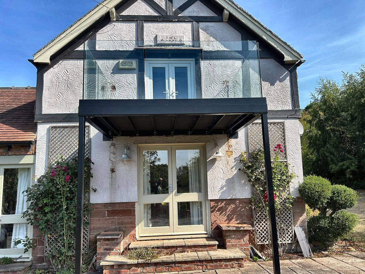 Post-supported walkout balcony with frameless glass balustrade and composite decking, Malpas, Cheshire