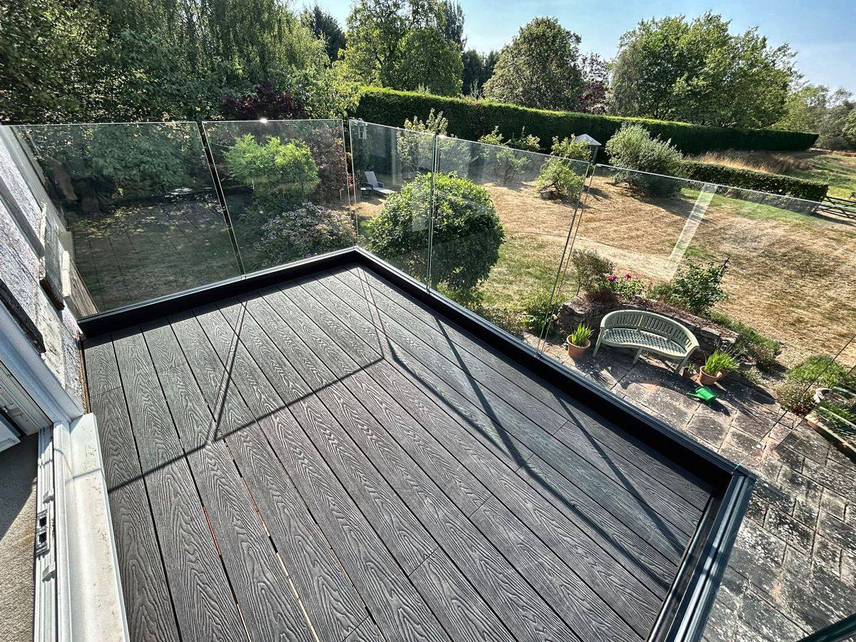 View across the garden from a frameless glass balcony balustrade, Cheshire
